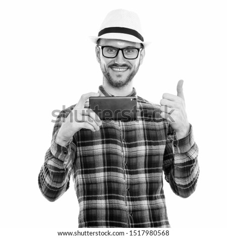 Studio shot of happy young man smiling while taking picture with mobile phone and giving thumb up