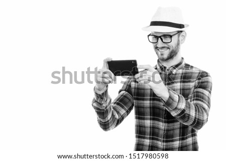 Studio shot of happy young man smiling while taking picture with mobile phone