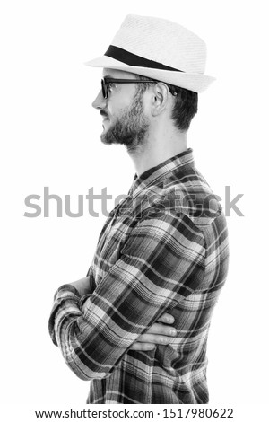 Profile view of young man wearing hat and eyeglasses with arms crossed