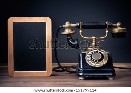 Vintage old telephone, black board frame on wood table