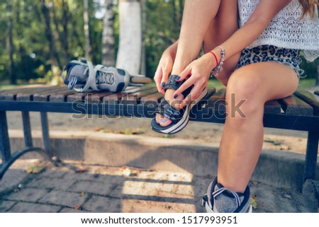 young woman dresses up rollers sitting on a park bench