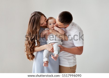 Happy young family. Beautiful Mother and father kissing their baby . Parents, Portrait of Mom, dad and smiling child on hands isolated over white background.