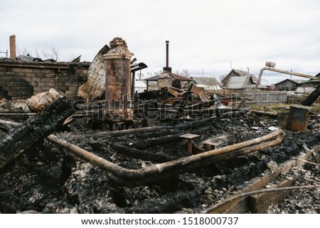 House after fire. Destroyed walls and interior. Smouldering ruins. The wreckage of home and life. Black charred walls of a wooden house, burnt household items.