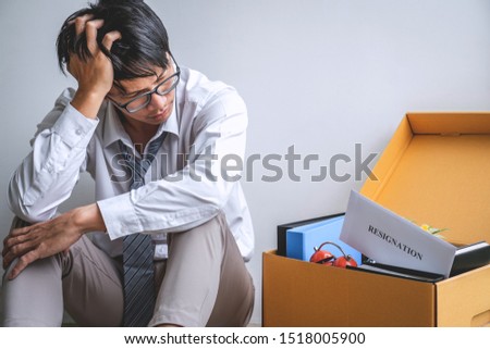 Images of packing up all his personal belongings and files into a brown cardboard box, Businessman has frustrated and stressed to resignation and signing cancellation contract letter in office.