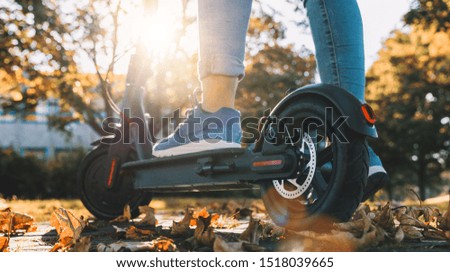 young woman on the electric scooter on the road in autumn at sunset Royalty-Free Stock Photo #1518039665