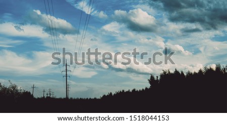 Evening sky at sunset background. Dark clouds hanging above horizon. Majestic cloudscape with power line. Grey cloudlets bringing rain. Countryside skyline in twilight time