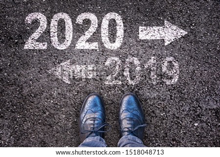 2020 and 2019 with direction arrows written on an asphalt road background with legs Royalty-Free Stock Photo #1518048713