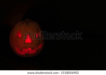 Halloween Symbol. Carved from pumpkin scary and terrible lantern Jack with a candle inside on a black background.