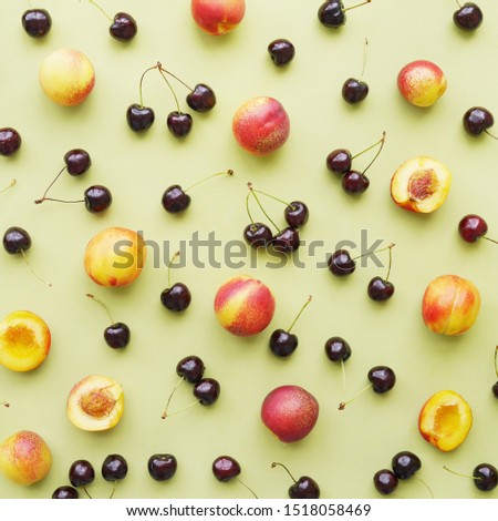 Cherry and peaches on a green background flat layout top view. Fruits pattern. 