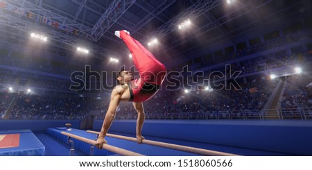 Male athlete doing a complicated exciting trick on parallel bars in a professional gym. Man perform stunt in bright sports clothes