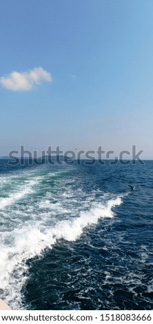 Blue clear sea and blue sky and waves behind the boat breaking on the sea  with birds in summer