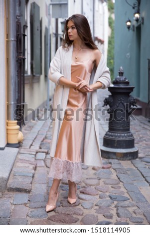 A beautiful woman in a light summer gown on the background of an old town.