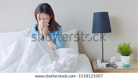 asian woman sick and sneeze with tissue paper in the bedroom
