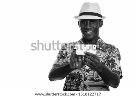Young happy black African man smiling and taking picture with mobile phone