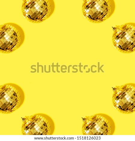 Frame with New year baubles. Shiny gold disco balls on yellow background. Pop disco style attributes, retro concept. Creative Christmas pattern. Flat lay, top view