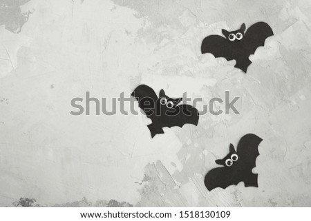 Halloween holiday concept. Black paper bats on a gray concrete wall background. Copy space