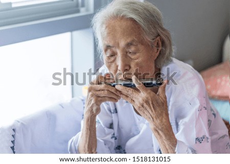Old man blowing a harmonica in nursing homes