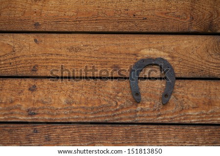 Old iron rusty metal horseshoe on weathered wood plank background