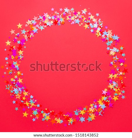 Festive red background with multicolor star shape confetti, copy space. Background for birthdays, christmas, anniversary