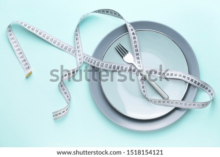Fork with plates and measuring tape on color background. Concept of diet