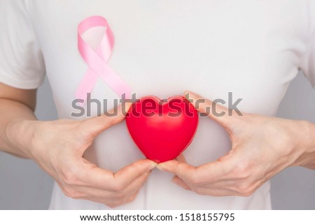 World Breast Cancer Day Concept,health care - woman wore white t-shirt,holding red heart and Pink ribbon for breast cancer awareness, symbolic bow color raising awareness