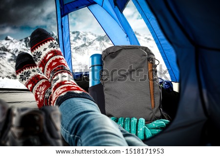 Winter photo of travel time. Blue ten interior with legs and christmas socks. Travel backpack and free space for your decoration. 