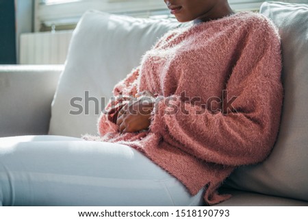 Woman in painful expression holding hands against belly suffering menstrual period pain, lying sad on home bed, having tummy cramp in female health concept Royalty-Free Stock Photo #1518190793