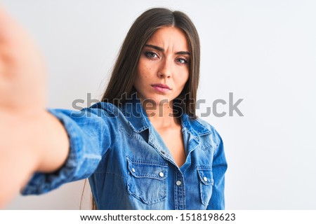 Beautiful woman wearing denim shirt make selfie by camera over isolated white background looking sleepy and tired, exhausted for fatigue and hangover, lazy eyes in the morning.