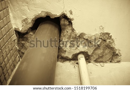Residential apartment in a multi-storey residential building in the city. Replacing the old cast-iron sewer pipe with a plastic one. Black and white photography. Sepia