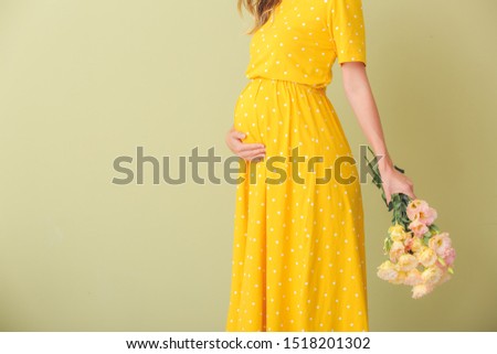 Beautiful pregnant woman with bouquet of flowers on color background