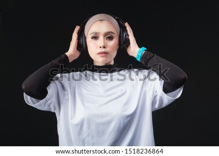 A Beautiful hijab girl wearing a smart band watch and headphone with various pose. dark background, studio light