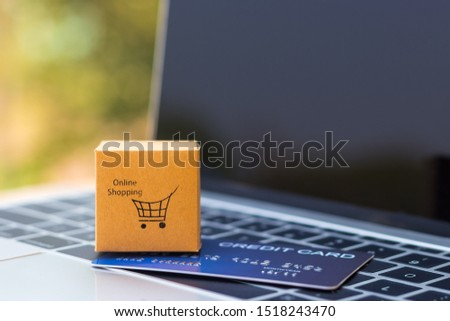 Online shopping and ecommerce concept. Cardboard box with symbol and mock-up of credit card on laptop keyboard with copy space. Consumer buy product directly anywhere anytime from seller using website