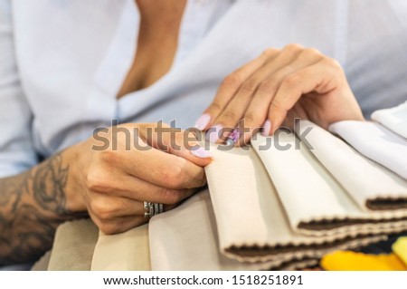 A young women looks at tissue samples. Selects the color of the sofa. Textile industry background.