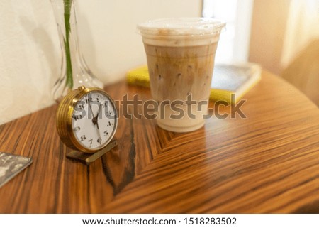 Alarm clock with iced coffee on table at cafe