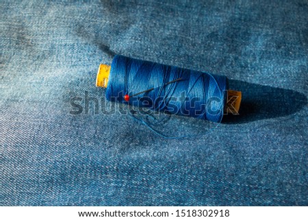Spool of thread on a blue jeans with a round head pin put in the spool, picture taken in the Netherlands