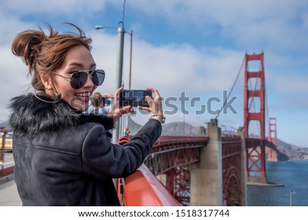 Woman Tourists use smartphone  take a photo visiting the world-famous Golden Gate Bridge of San Francisco in California America.Travel Lifestyle and vacation concept.