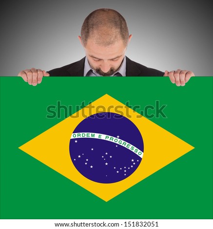 Smiling businessman holding a big card, flag of Brazil, isolated on white