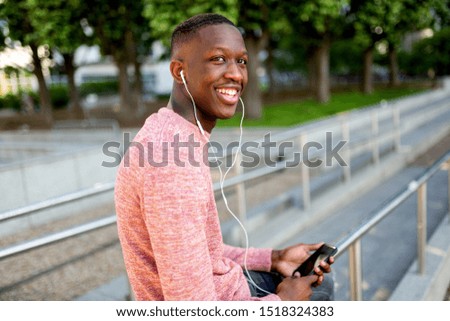 Portrait of smiling young african american man listening to music with headphones and mobile phone