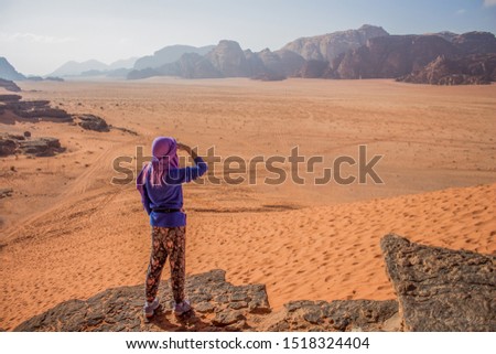 travel photography life style concept picture of girl back to camera stay on mountain edge and looking from above on desert wasteland sand valley with mountain background 