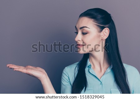 Close up photo of cheerful atractive business lady holding ads with her hands staring at palm wearing formally isolated over grey color background