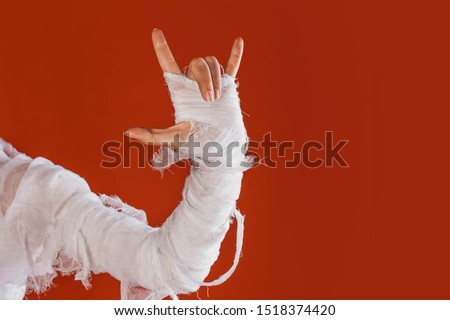 Halloween, costume image. The mummy's hand in bandages making gestures. Super gesture, rock n roll and metal music, Halloween party