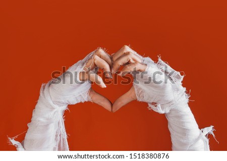 Halloween, costume image. The mummy's hand in bandages making gestures. Love you, sweet mummy shows heart sign by hands