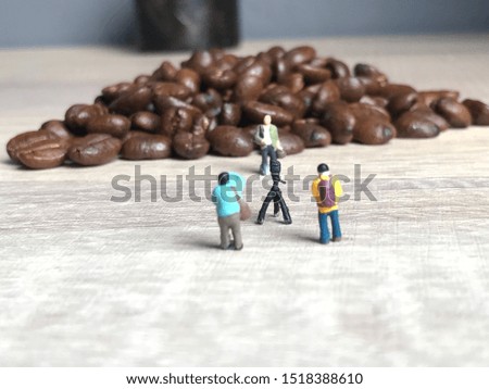 Miniature People are taking pictures on a pile of Coffee Beans