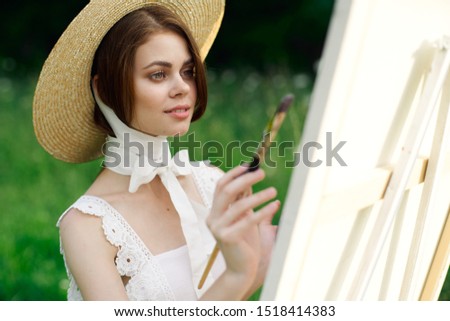 woman looks at a white canvas with a brush in her hands