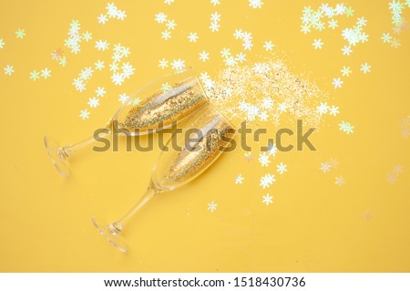 Champagne glasses with gold confetti, glitter yellow background. new year celebration. Top view. The concept of celebration.