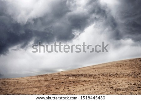 Sandstorm in a dry desert under a cloudy sky with dark clouds