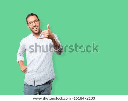 Amazed young man making a gesture of calling with the hand