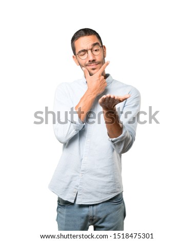 Doubtful young man holding something with his hand