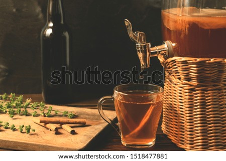 Fresh homemade Kombucha fermented tea drink in jar with faucet and in cup and bottle on black background