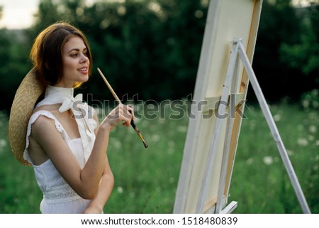 beautiful woman model in a forest a painting paints an easel